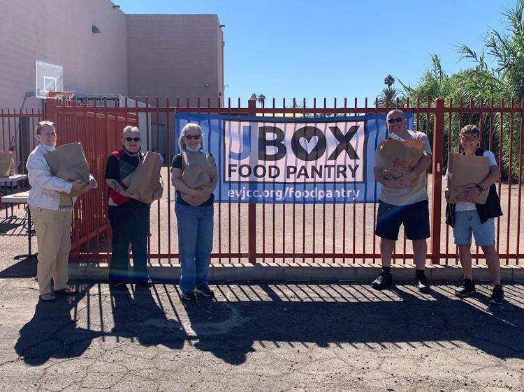 photos of volunteers lined up in front of a gate carrying bags of food that are given out at the kosher food pantry