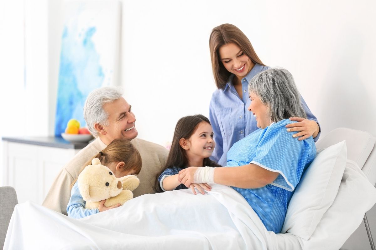 photo of a family with two kids comforting a loved one in a hospital bed