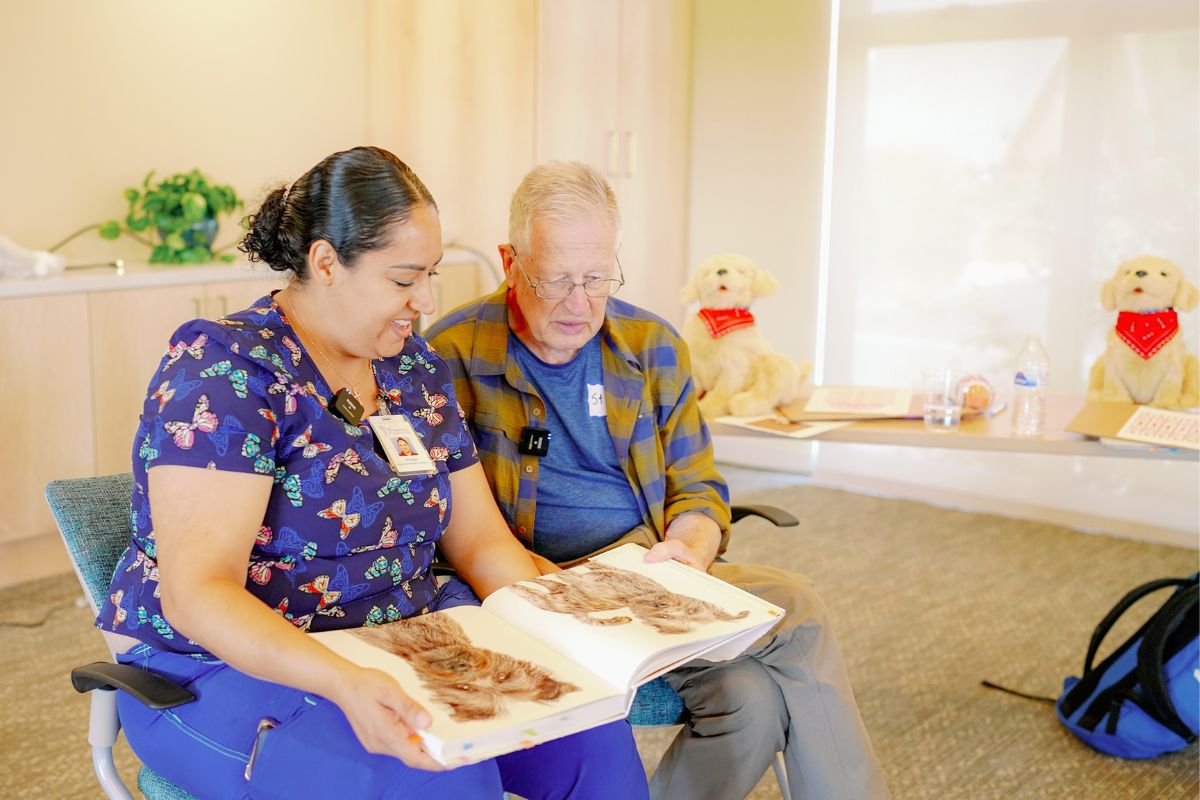 Dementia respite caregiver Sonja Marti pages through a dog book that interests Stephen Campbell.